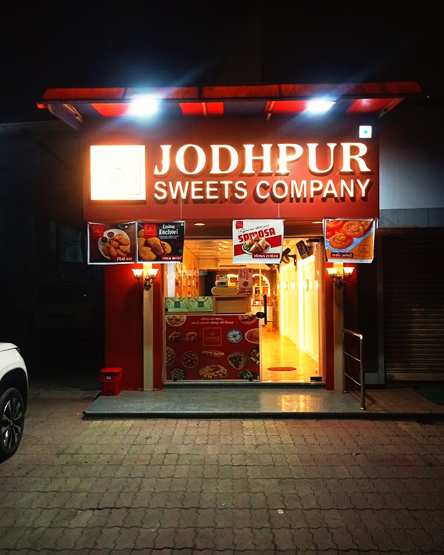 The lit Jodhpur Sweets Company sign at night